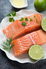 Close-up of raw sliced salmon fillet on ice with dill, parsley and lime, selective focus, studio shot