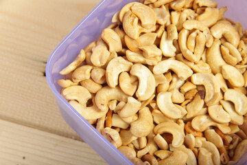 Fried splited cashews on a wooden table, a tasteful snack