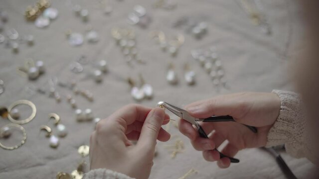 Jewelry designer working with tools making pearl earrings