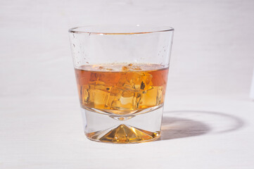 Glass of alcohol drinks with ice cubes on white