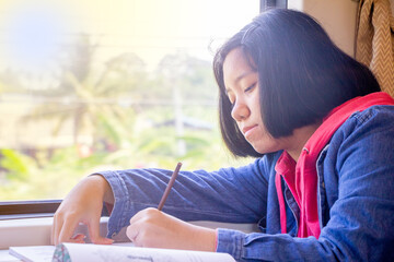 Asian teenager writing book or drawing picture on table