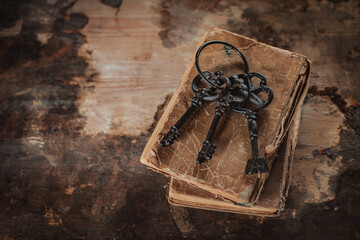old vintage keys on an old battered book, wooden background.