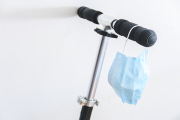 surgical mask hanging from a black scooter handle bar. Selective Focus.