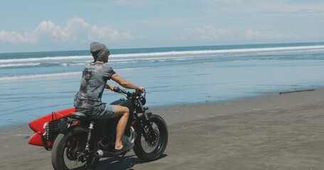Obraz na płótnie Canvas Motorcyclist driving his motorbike on the beach