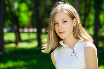 Fototapeta premium Portrait of a young beautiful brunette girl in summer park