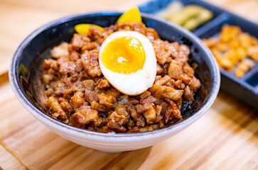 Taiwanese Minced pork rice with an egg and pickled vegetables on wooden table and tray