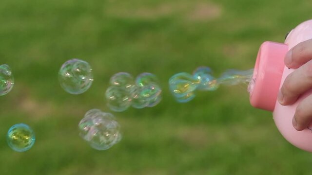 Close up many blowing bubbles from bubble gun. Blur green grass background. 
