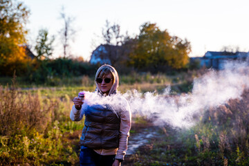 A woman holds a steaming bowl in her handsagainst house in the country.  Concept: human impact on...