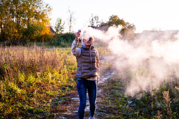 A woman holds a steaming bowl in her hands against house in the country.  Concept: human impact on...
