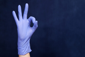 Hand in a protective latex glove shows OK to the viewer. The concept of successful operation, the completion of hard work.
