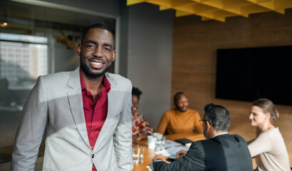 Smiling African businessman standing in a boardroom during a meeting