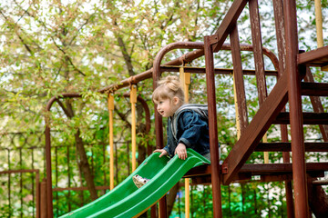 Obraz premium Cute baby girl on a seesaw swing at the playground.Cute baby girl on a swing seesaw. on the playground in the park outdoors. walk in kindergarten