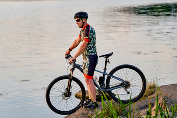Fototapeta na wymiar Mountain biker looking at view and traveling on bike. Lake landscape.