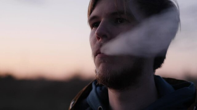 Portrait of a young man on the road Smoking electronic cigarettes closeup