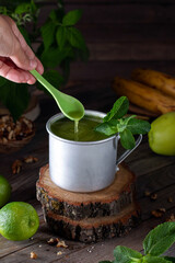 Detox. Green drink in a metal mug with mint on an wooden table