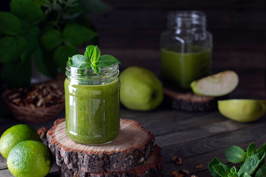 Green smoothie made of green organic apple, mint and spinach on wooden background. With copy space