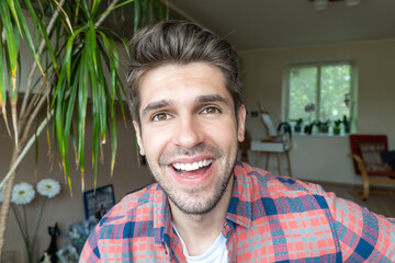 Portrait of a young cheerful latin guy with a wide open smile sitting in a shirt 