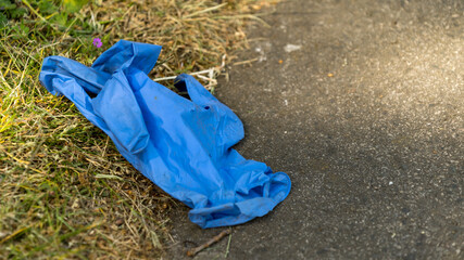 Used blue disposable protective glove dropped on the floor during COVID pandemic (UK)