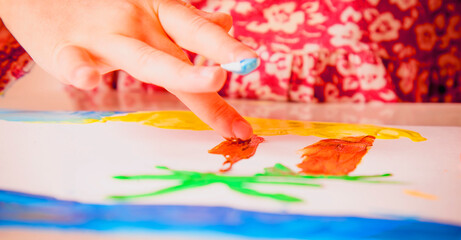 Great artist. Close up cute child girl painting a picture with finger. Painting process and education concept. Horizontal image.