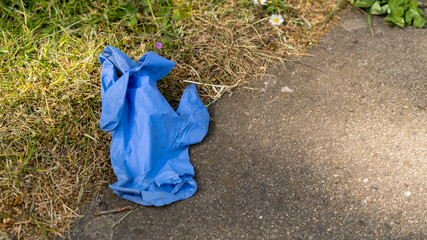 Used blue disposable protective glove dropped on the floor during COVID pandemic (UK)