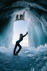 Fototapeta premium A person standing next to an ice waterfall cave