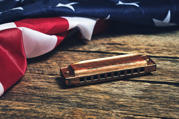 Flag of the United States of America and harmonica on a wooden background.