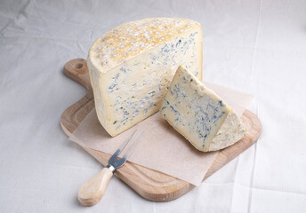 Homemade cheese on wooden plate at light background.