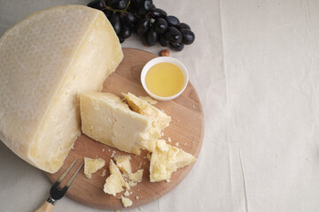 Homemade cheese on wooden plate at light background.