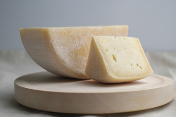 Homemade cheese on wooden plate at light background.