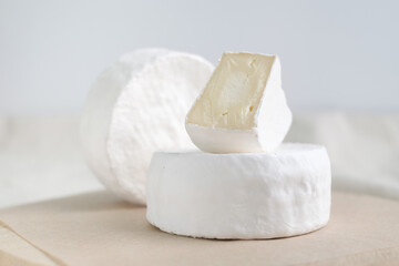 Homemade cheese on wooden plate at light background.