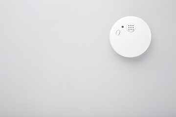 White new smoke alarm on light gray background. Safety concept. Empty place for text.