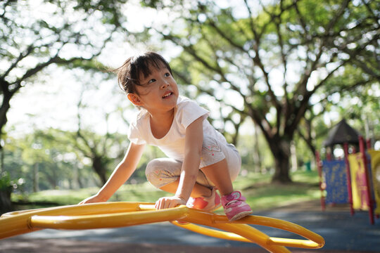 Asian chinese girl managing playground obstacle on her own