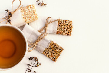 Fototapeta na wymiar Cup of tea and homemade kozinaki from sunflower seeds, sesame on Jerusalem artichoke syrup on a white background.Сoncept of healthy food and healthy desserts.Top view,copy space