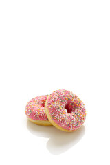 Two donuts with pink icing and colored sprinkles on a white background.