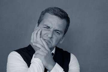 A man holds his cheek from a toothache.