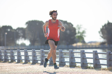 Hombre joven practicando running en el parque junto a un lago