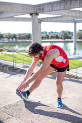 Joven runner haciendo estiramientos en el parque después de practicar ejercicio físico