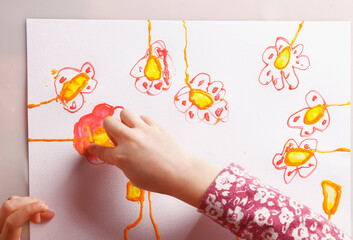 Top view of little cute girl enjoying her painting. Close up hands and finger of child.