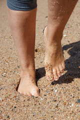 Obraz na płótnie Canvas Walk on the sand, on the beach, on the beach. Health. Close-up of a woman's legs.