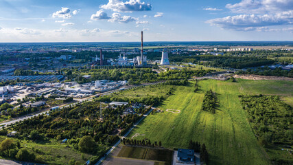 Widok na komin fabryki rejonu przemysłowego z chmurami rzucającymi cień na pobliskie obszary,...