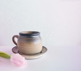 Ceramic cup  and pink tulip on a light background