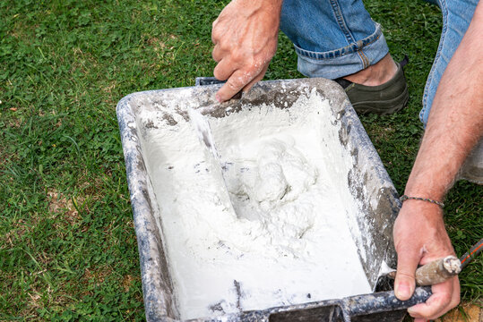 homme pr&eacute;parant du ciment pour des travaux dans son jardin
