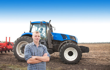 Young attractive man near a tractor. Concept of agriculture and field works.