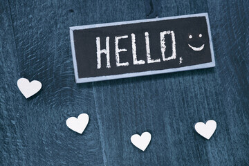 Hello and white hearts on blue wooden background