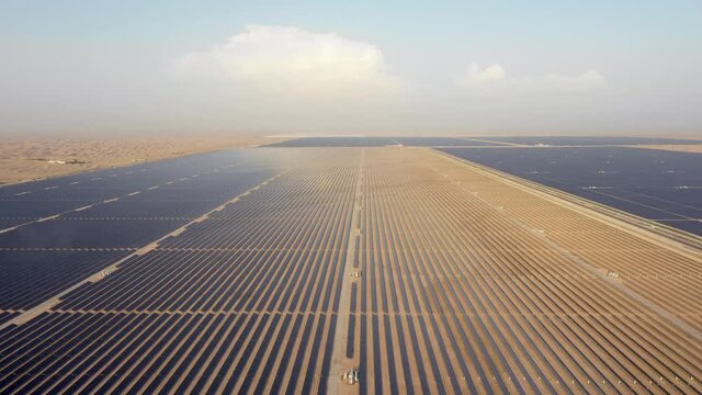 Aerial view from a drone flying high over photovoltaic panels in a desert solar farm.