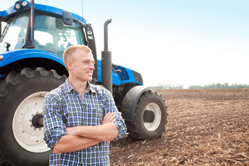 Young attractive man near a tractor. Concept of agriculture and field works.