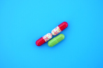 Three bright medical capsules on a bright blue isolated background with space for text.