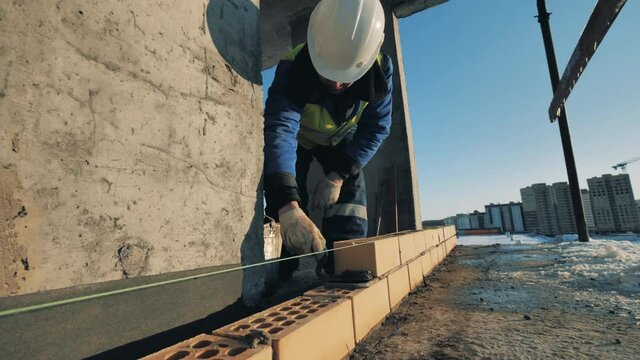Construction site, construction industry, construction worker concept. Builder levels bricks with a string on a site.