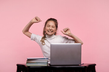 student girl sits at a desk with a laptop and does while sipping.