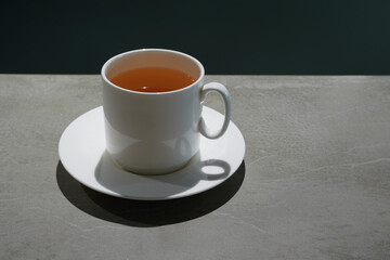 White ceramic cup with green tea on a dark table.